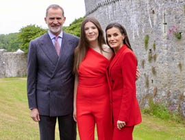 a group dressed in formal attire posing outdoors beside a stone wall