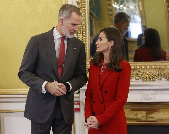 los reyes, a juego de rojo, en el palacio real de aranjuez