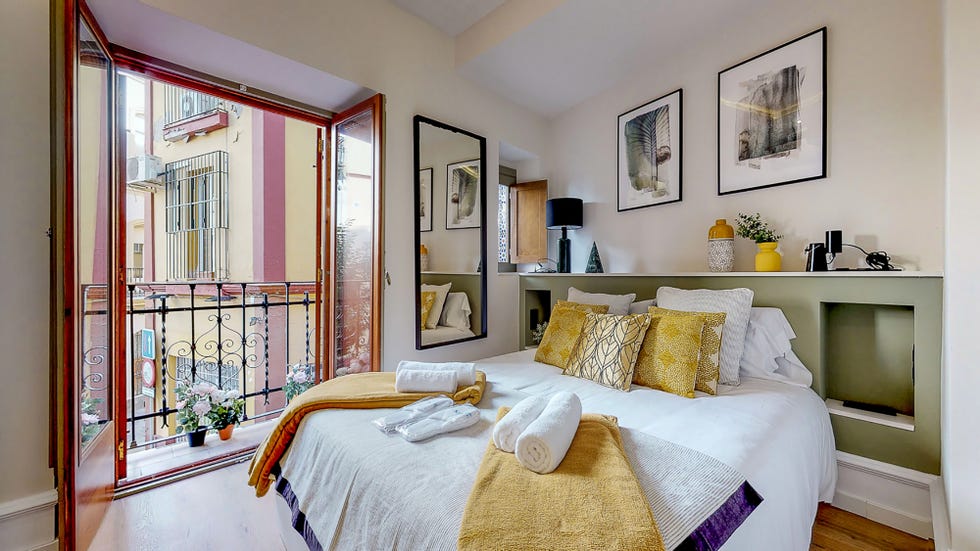 dormitorio con cabecero de obra en color verde y ventanas recuperadas