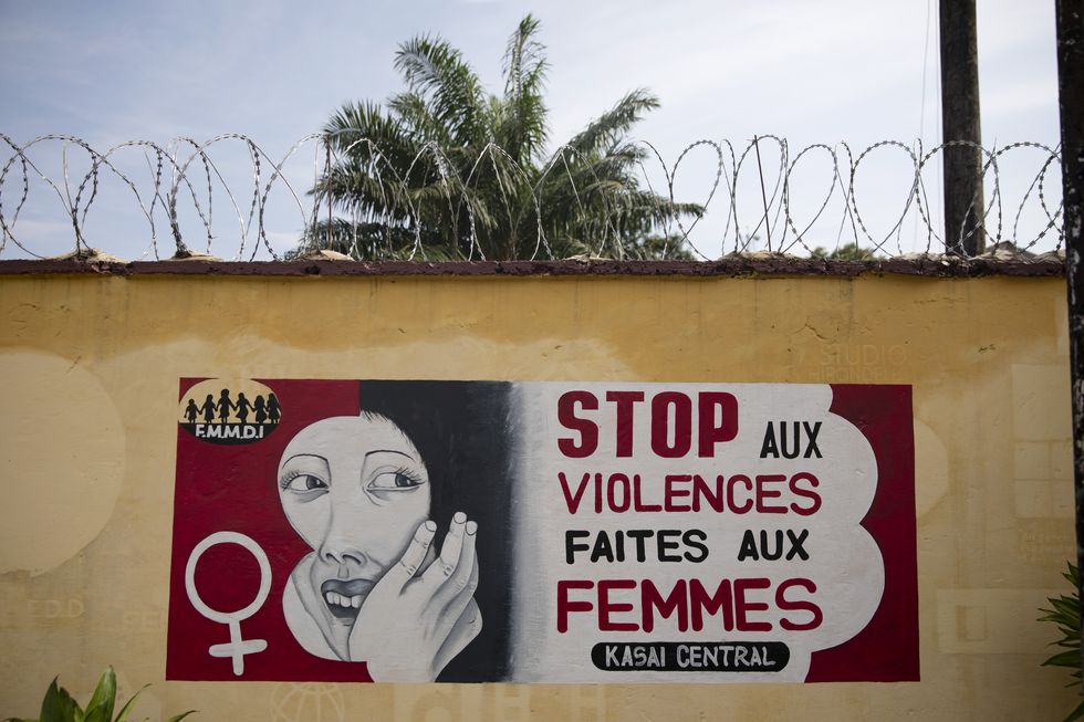 a red, black, and white painting that denounces gender based violence on a wall in the democratic republic of the congo