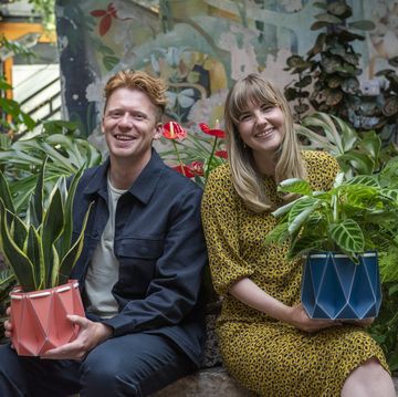 potr directors andrew flynn and eilidh cunningham sitting in green foliage holding colourful origami plant pots