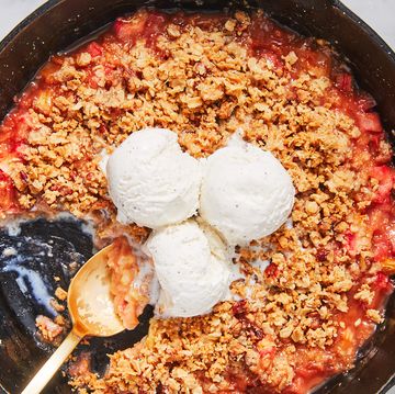 rhubarb crisp topped with scoops of vanilla ice cream in a black cast iron skillet