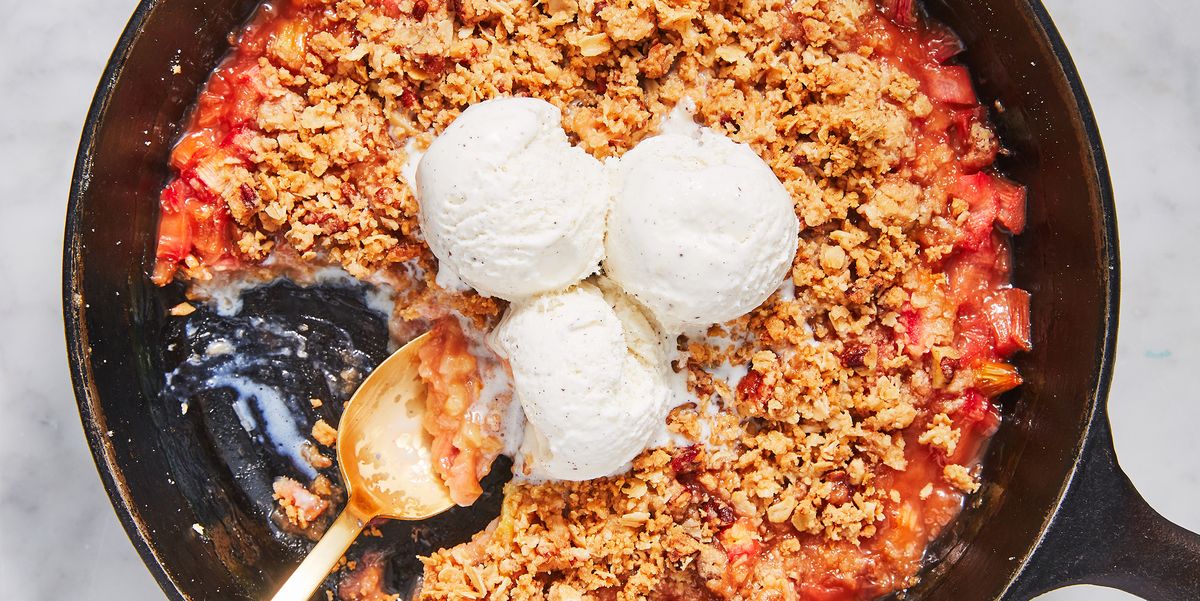 rhubarb crisp topped with scoops of vanilla ice cream in a black cast iron skillet