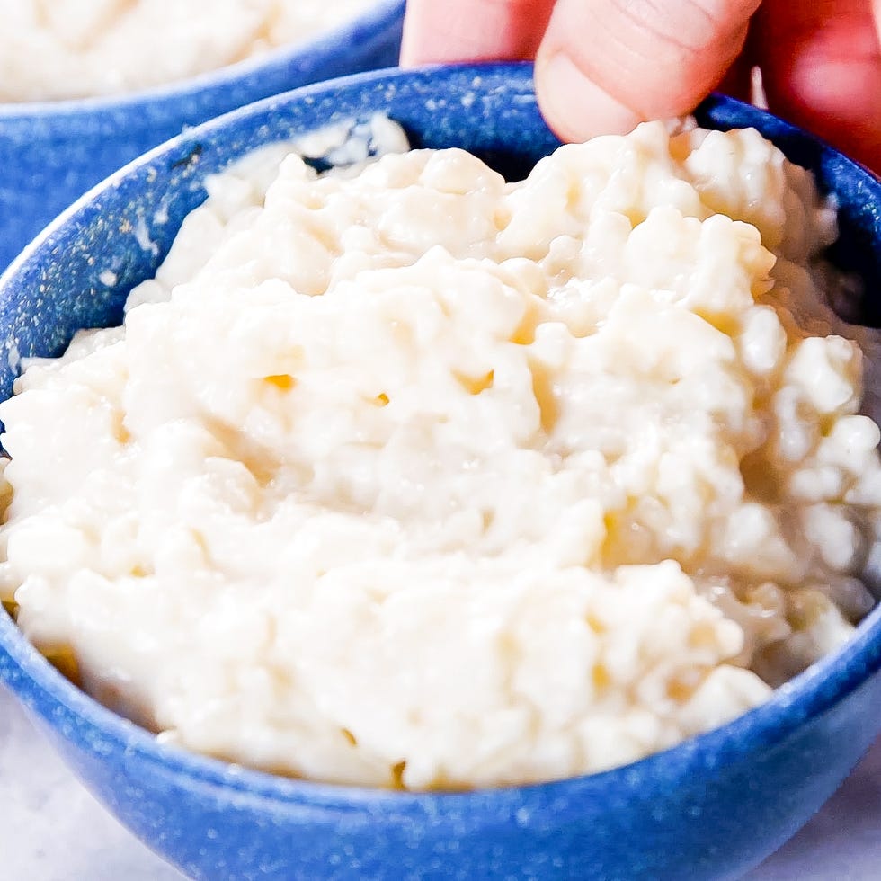creamy rice pudding in a blue bowl held by a hand