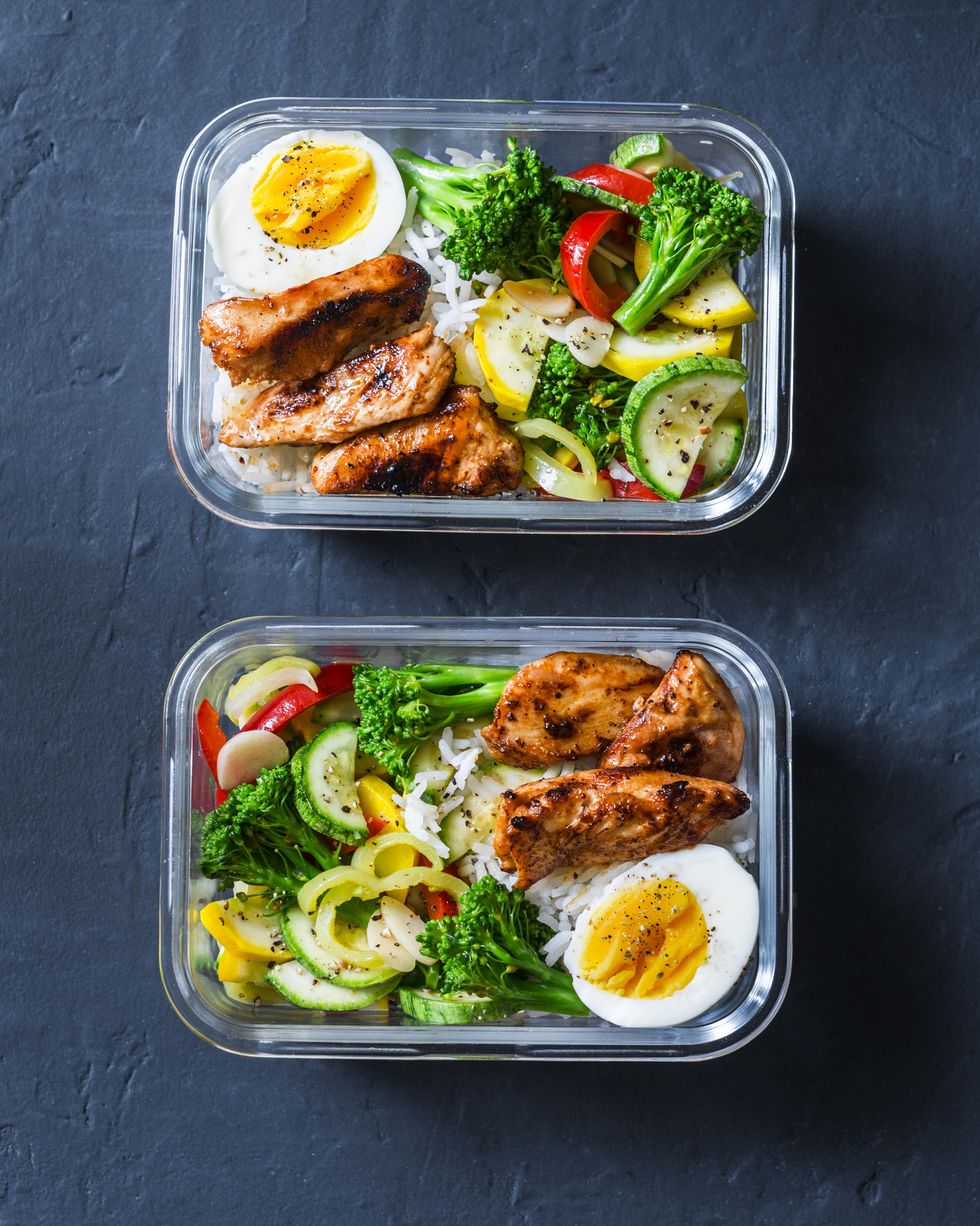 Rice, stewed vegetables, egg, teriyaki chicken - healthy balanced lunch box on a dark background, top view. Home food for office concept