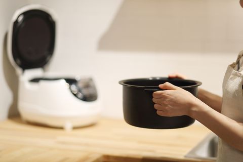 women holding rice cooker in kitchen