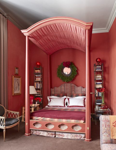 a red bedroom with a pleated canopy and tartan bedcover and pillow shams