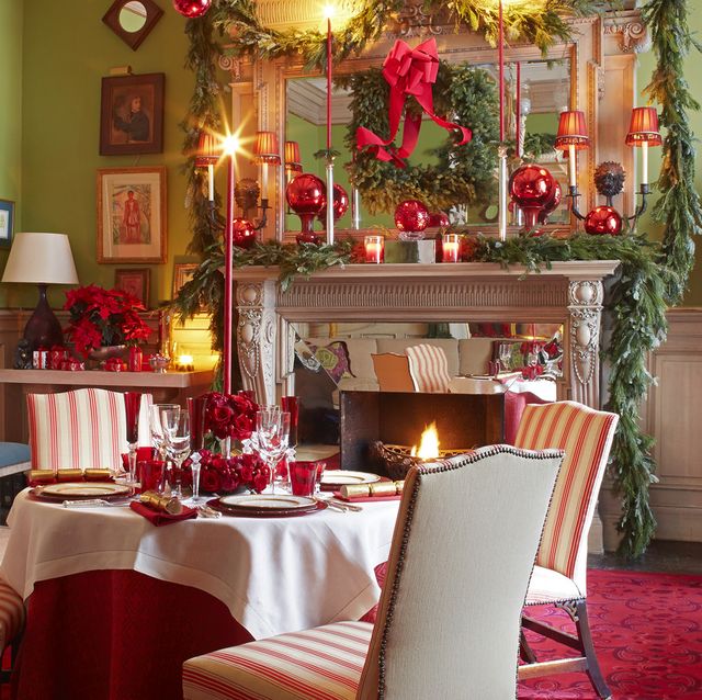 a living room turned dining room is set for a holiday party with decorations including garland and wreaths and candles