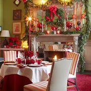 a living room turned dining room is set for a holiday party with decorations including garland and wreaths and candles