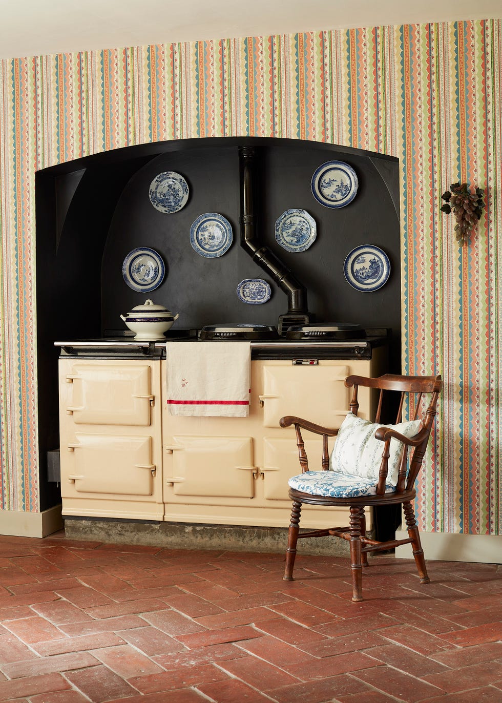 An AGA stove is placed in a black painted corner of the kitchen, and a plate is hung above it.