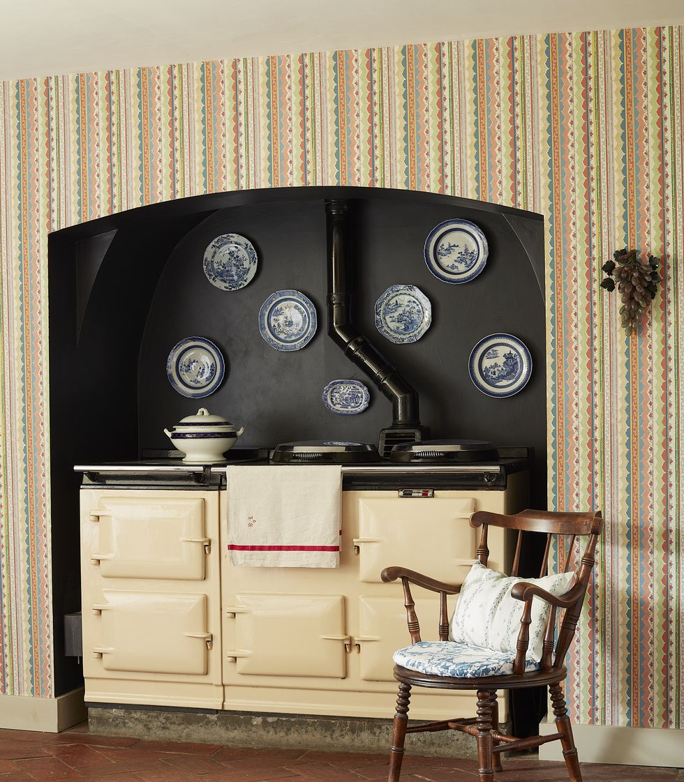 an aga stove is nestled in a nook painted black in the kitchen with plates hung above