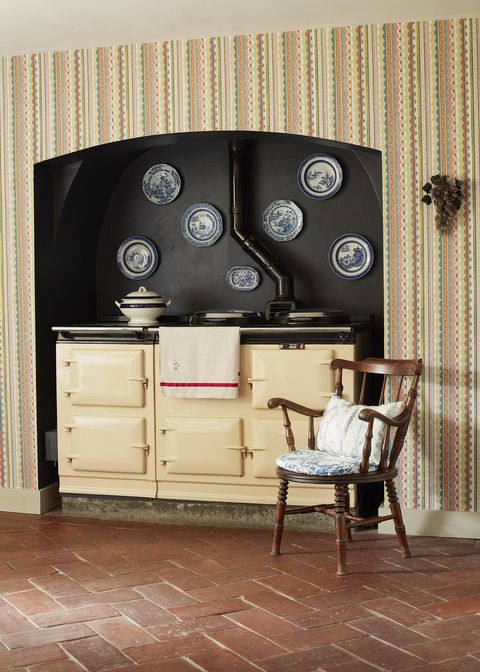 an aga stove is nestled in a nook painted black in the kitchen with plates hung above