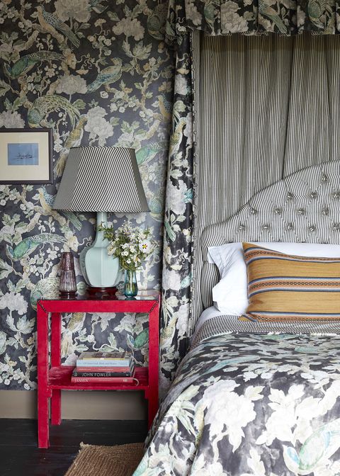 the master bedroom is a lesson in black and white stripes on the upholstered headboard and then floral wallpaper and matching bedding