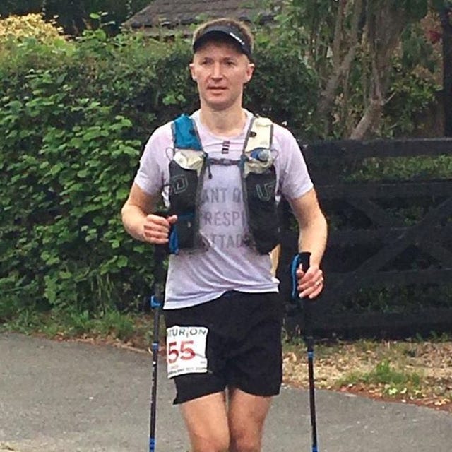 a man with a number on his shirt and shorts holding a pair of hiking poles