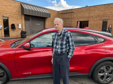 george chartier posing in front of a red mustang mache