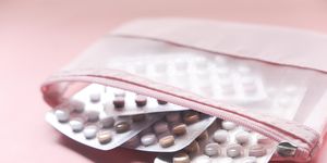 birth control pills on pink background, close up