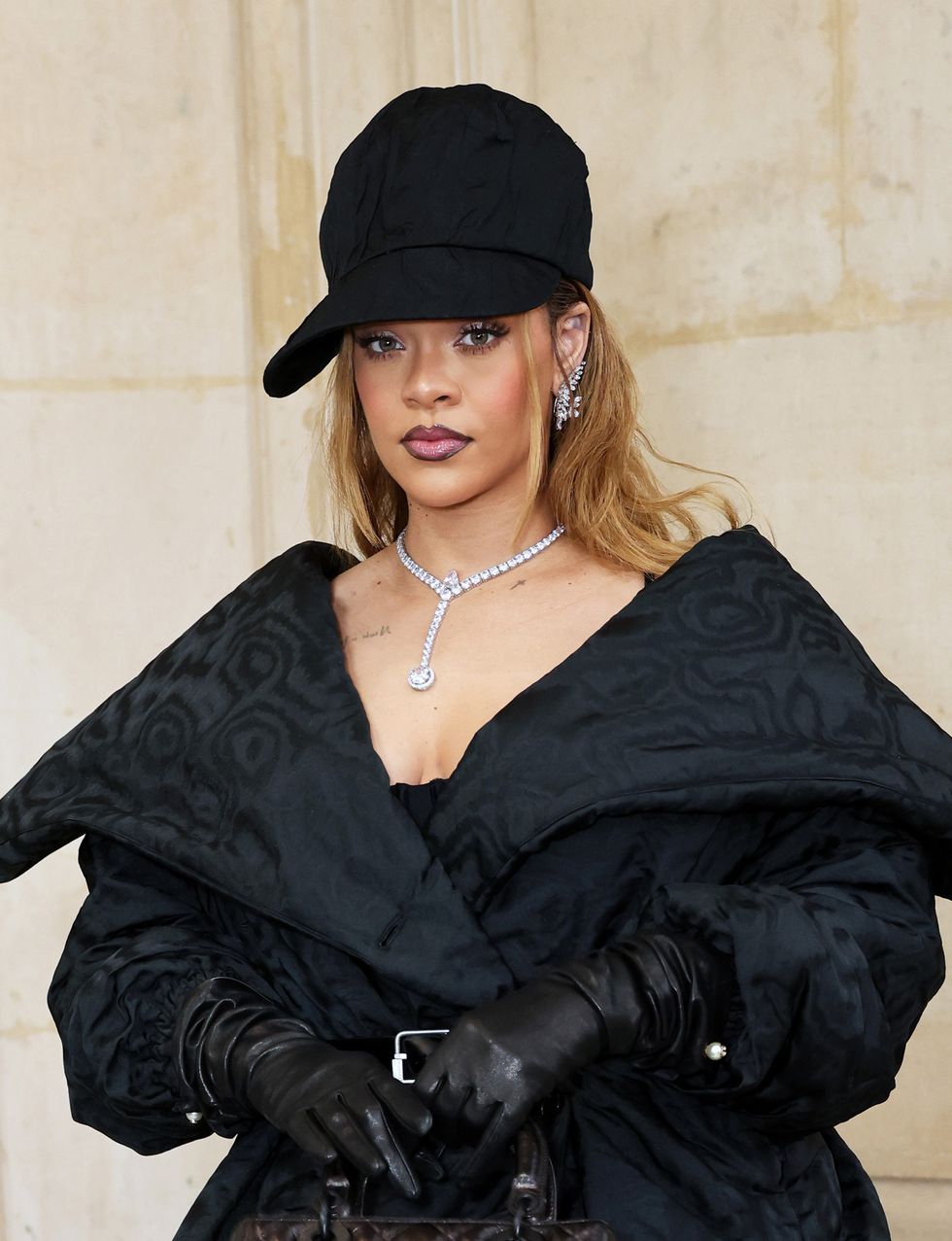 Rihanna Wears Black Belted Dress, Jacket, and Diamonds at Dior Show