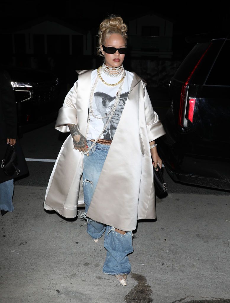 rihanna leaving a restaurant in los angeles wearing a white satin coat on top of a white top jeans and sunglasses