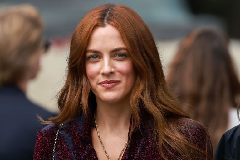 riley keough pictured at an event, wearing a blazer and star necklace
