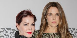 priscilla presley and riley keough on a red carpet where riley has her arm around her