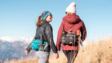 dos mujeres senderistas con mochila riñonera deportiva para hacer senderismo