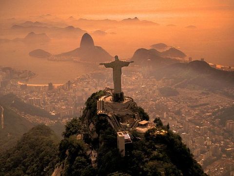Vanaf de top van de Corcovadoberg ziet Cristo Redentor Christus de Verlosser uit over de stad Rio de Janeiro Op de achtergrond bevinden zich de Sugarloafberg en de Guanabarabaai Bezoekers kunnen de taxi of tandradbaan nemen om te genieten van ongevenaard uitzicht op de stad