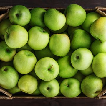 ripe and juicy green apples in a box on a wooden table,romania