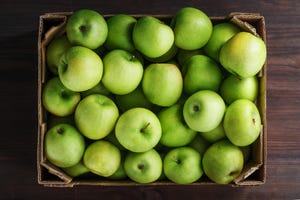 ripe and juicy green apples in a box on a wooden table,romania