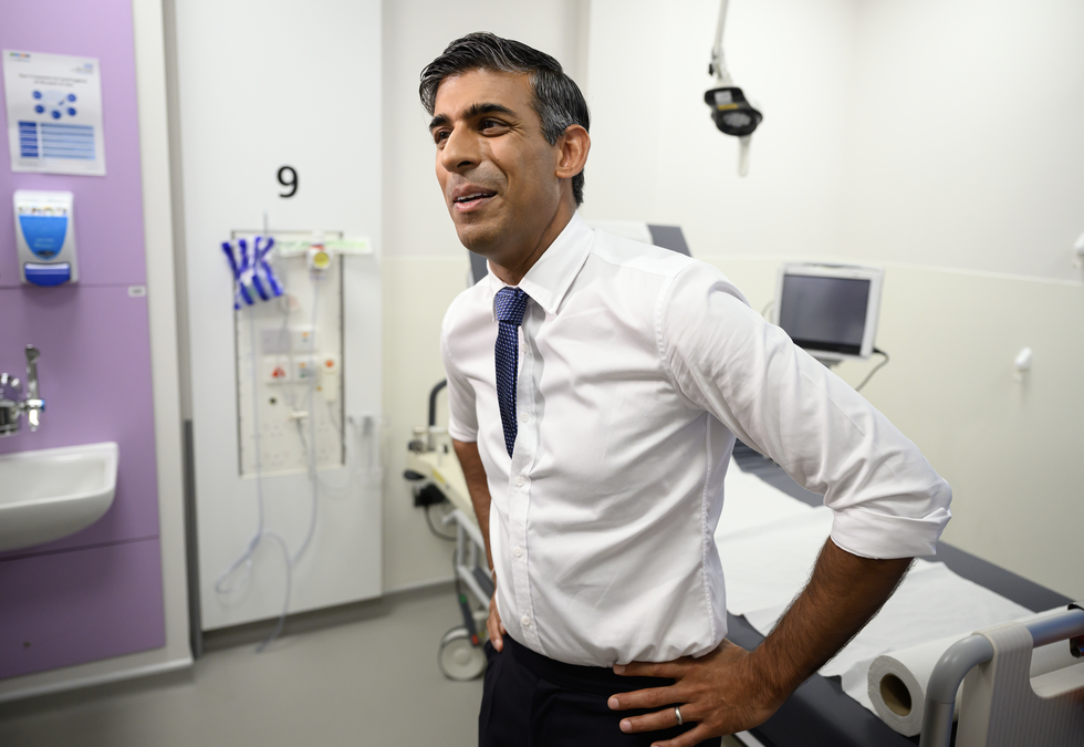 rishi sunak stands in front of a hospital bed