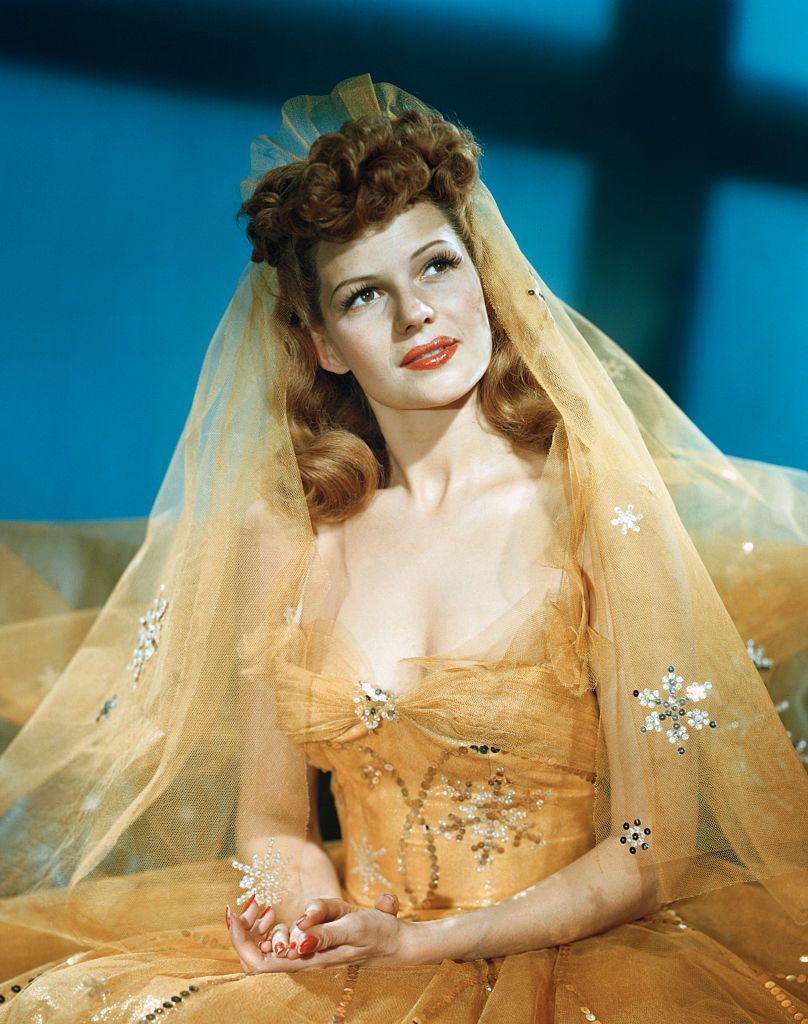 rita hayworth wears a yellow gown and veil