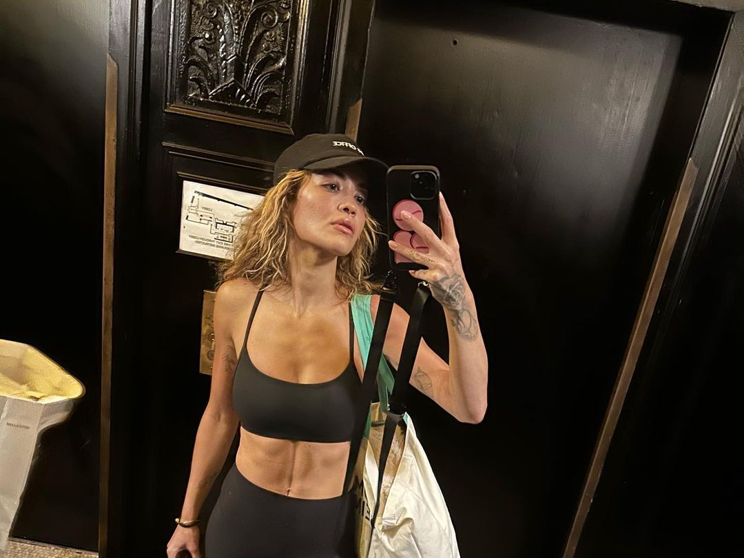 Rita Ora wears a black sports bra and leggings for selfie