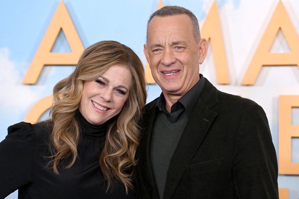 rita wilson leans against tom hanks as they smile for a photo at a film event