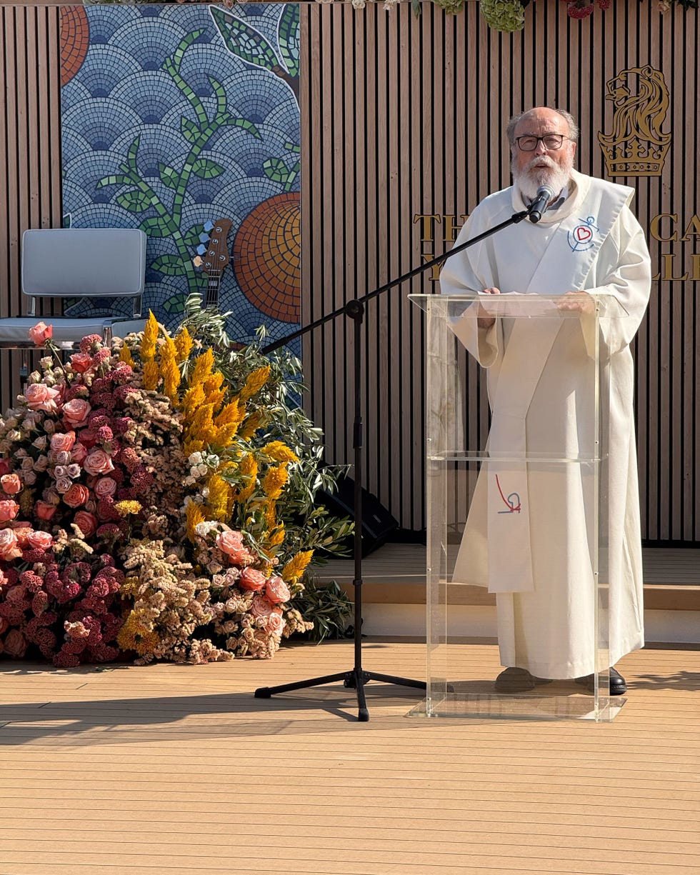 a person delivering a speech at a podium with a floral arrangement in the foreground