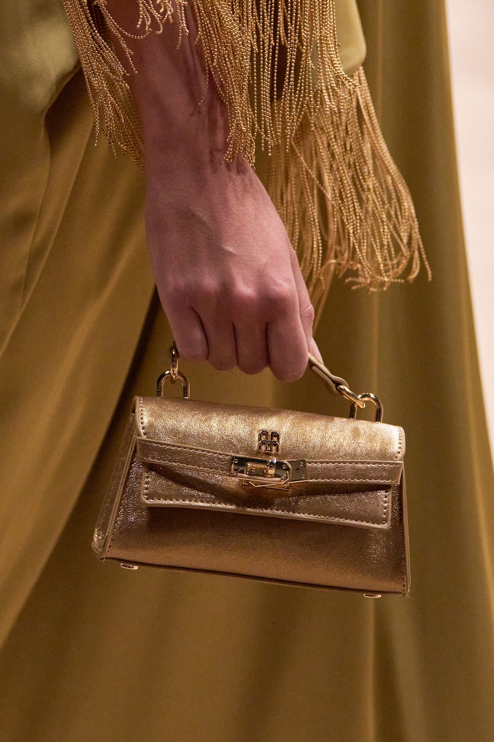 hand holding a small gold handbag