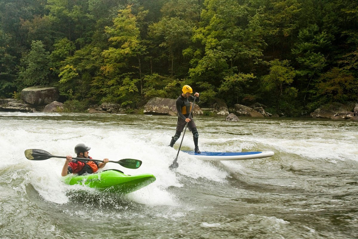 Een surfer en een kajakker op een golf op de benedenloop van de rivier Gauley bij Fayatteville in de Amerikaanse staat West Virginia