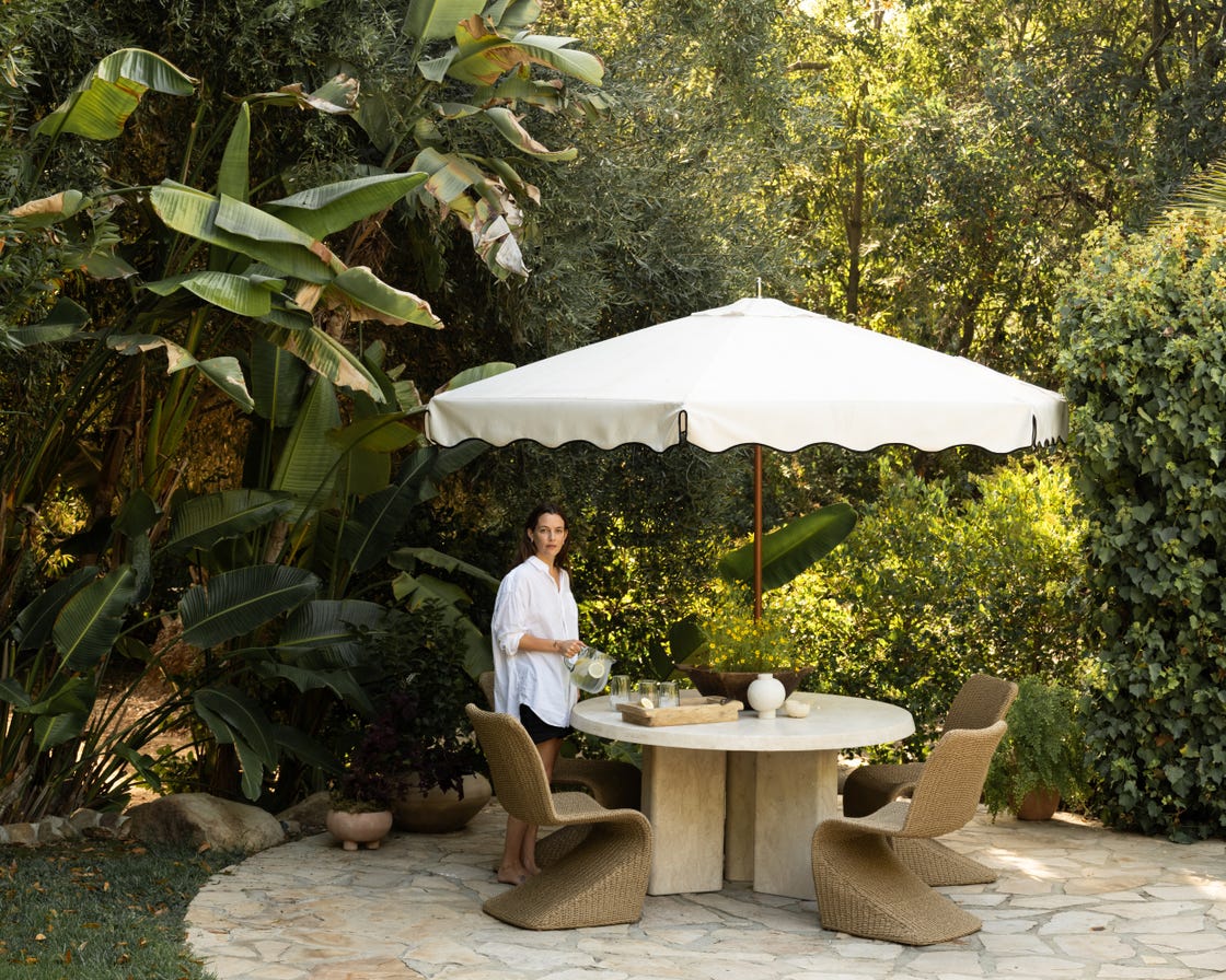 outdoor dining area under a large umbrella surrounded by lush greenery