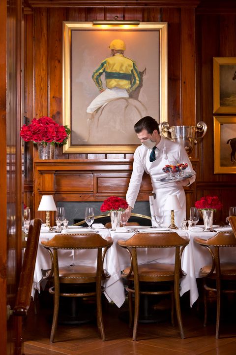 waiter with mask serves dinner at ralph lauren's polo bar clubroom