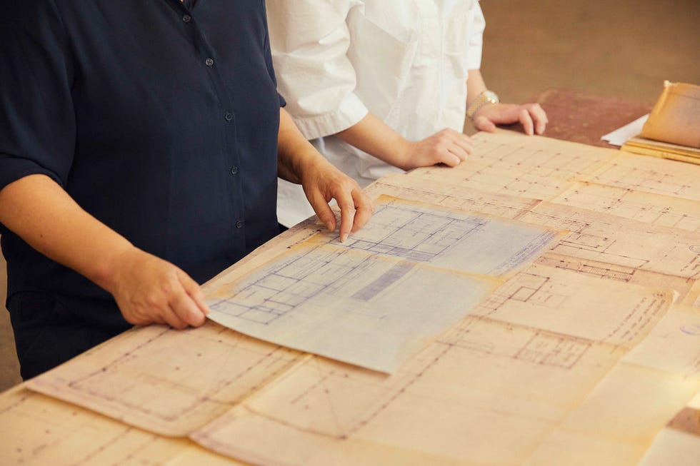 hands holding architectural blueprints on a table
