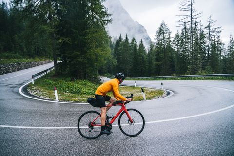 road bicyclist rides down a wet road in the rain
