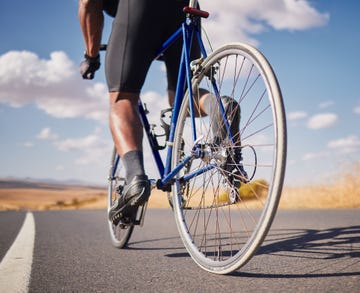 road, closeup and man on a bike for cycling, race training or travel in the countryside health, exercise and legs of male cyclist or athlete with a bicycle for a workout, street cardio or triathlon