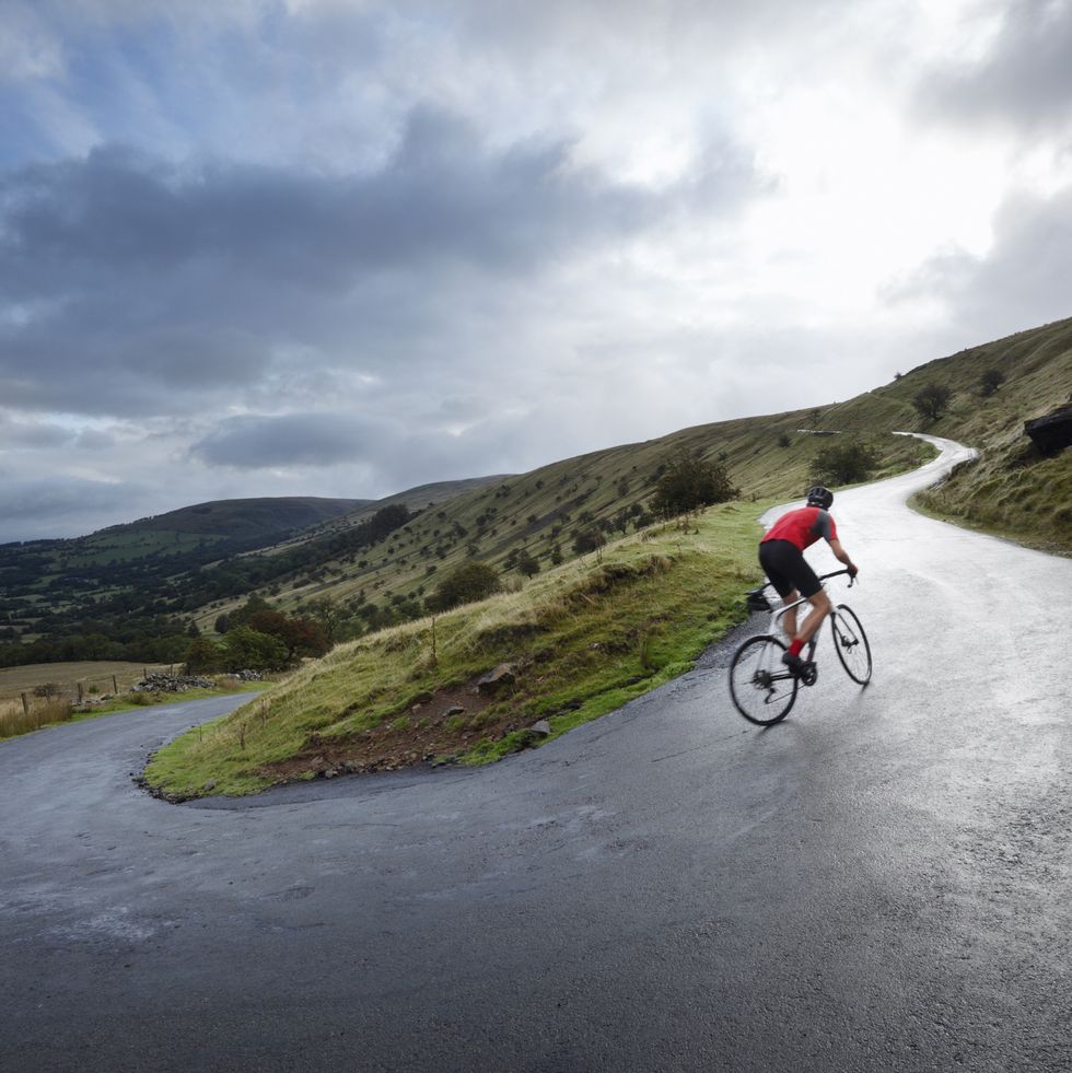 road cyclist climbing hairpin bends up hillside