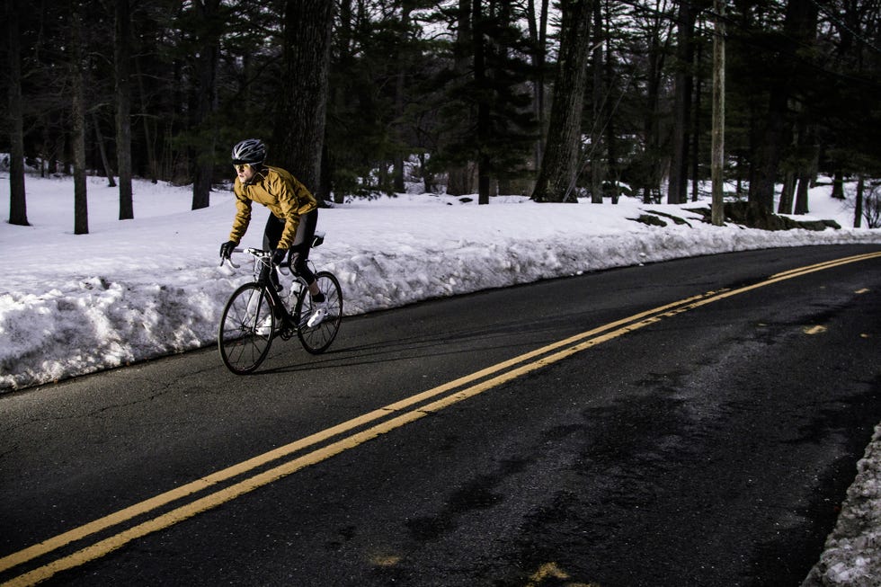 a road cyclist rides through a wintery landscape