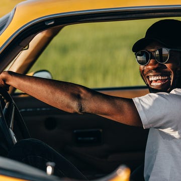 man in sunglasses and hat driving car