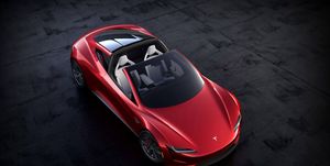 a red two door tesla sports car is shown from above sitting on black tarmac
