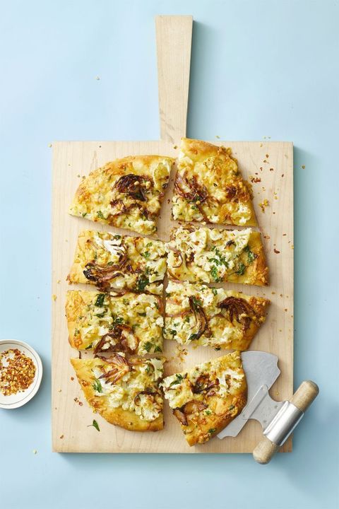 roasted cauliflower pizza on a wooden pizza board