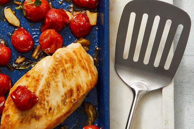 roasted chicken and tomatoes on a blue sheet pan