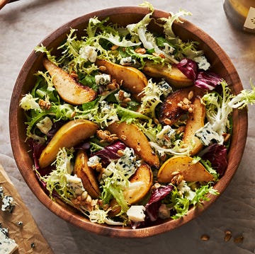 roasted pear salad with mixed greens, candied pepitas, and blue cheese in a wooden bowl