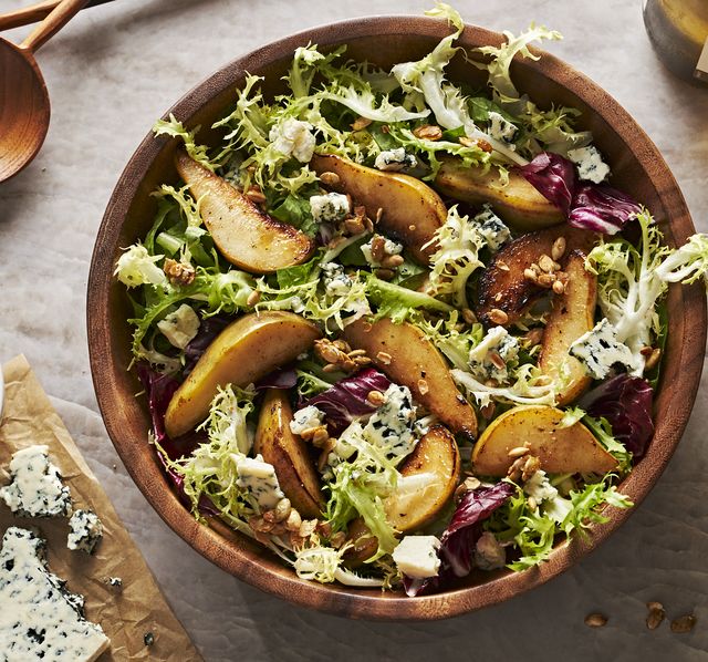roasted pear salad with mixed greens, candied pepitas, and blue cheese in a wooden bowl