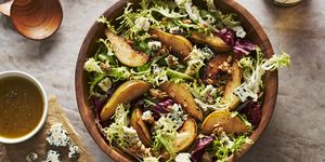 roasted pear salad with mixed greens, candied pepitas, and blue cheese in a wooden bowl