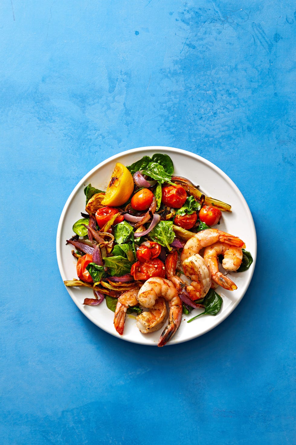 roasted shrimp tomatoes and spinach on a white plate